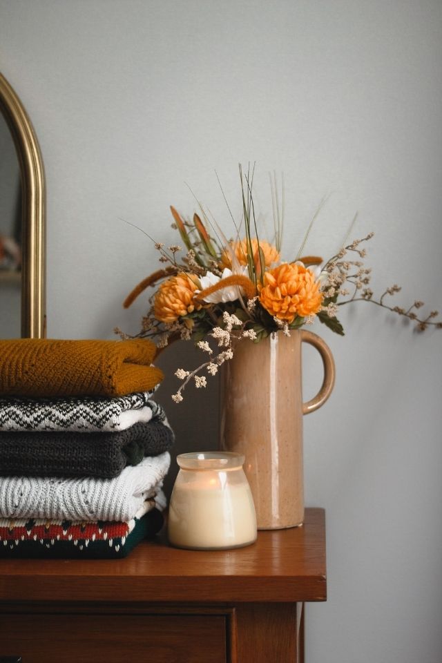 Thanksgiving decor flower arrangement on top of dresser with candles and orange flowers